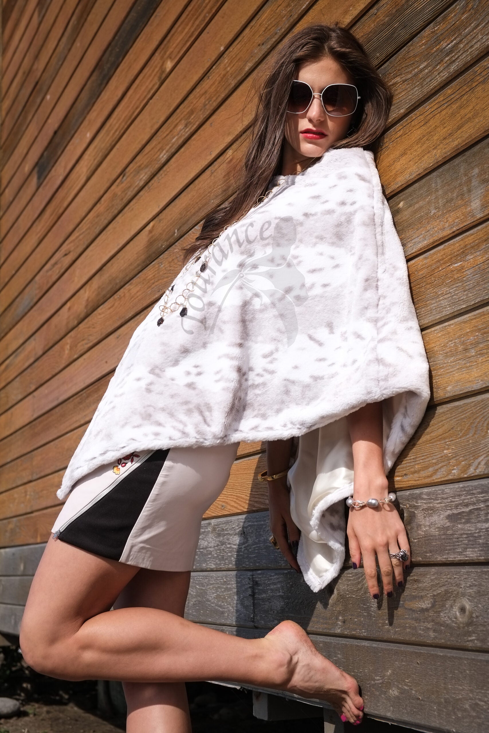 Woman wearing a Snow Grey Leopard Poncho leaning on wall